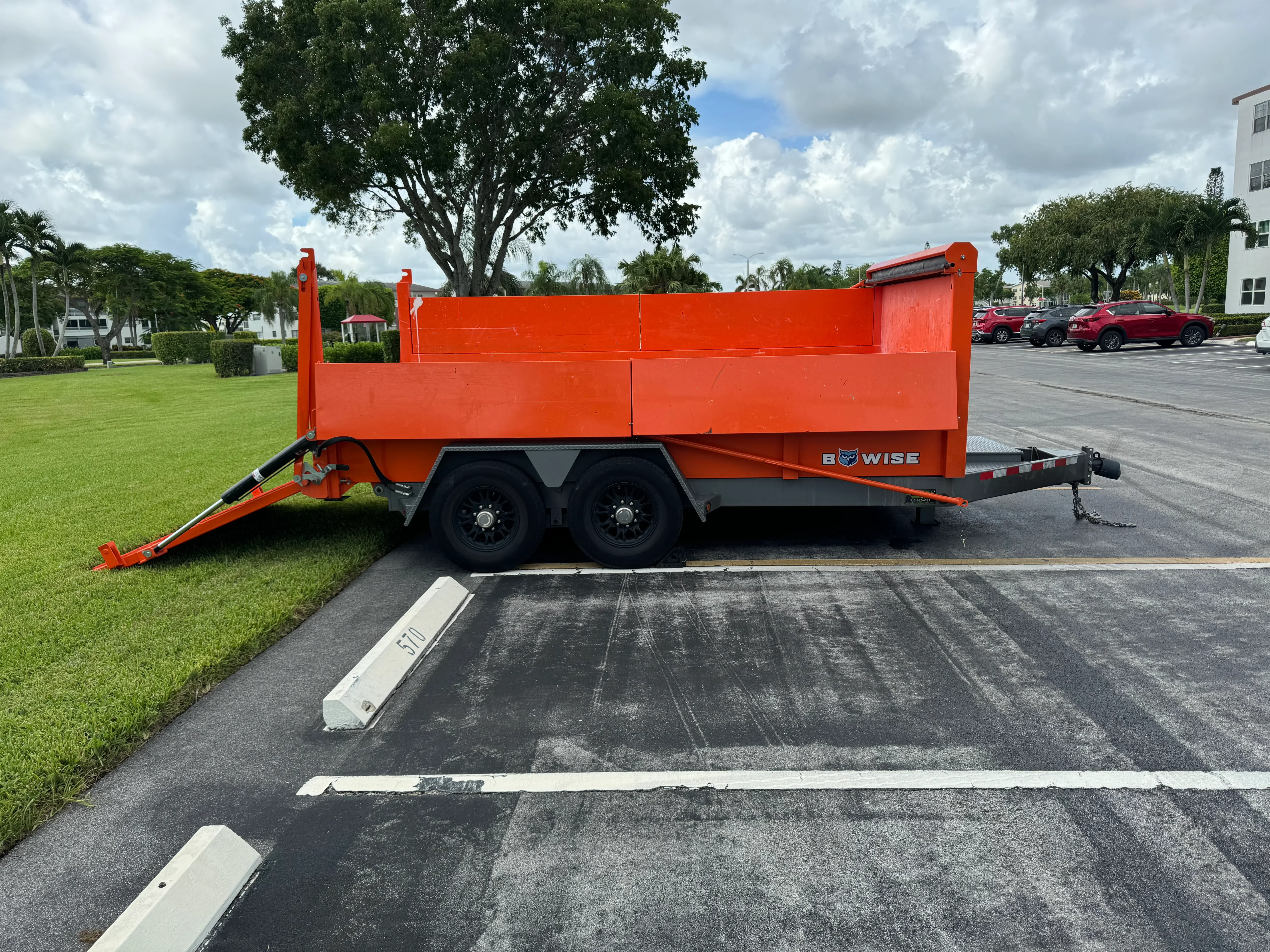 Orange dual axle dump trailer with hydraulic lift gate and steel construction
